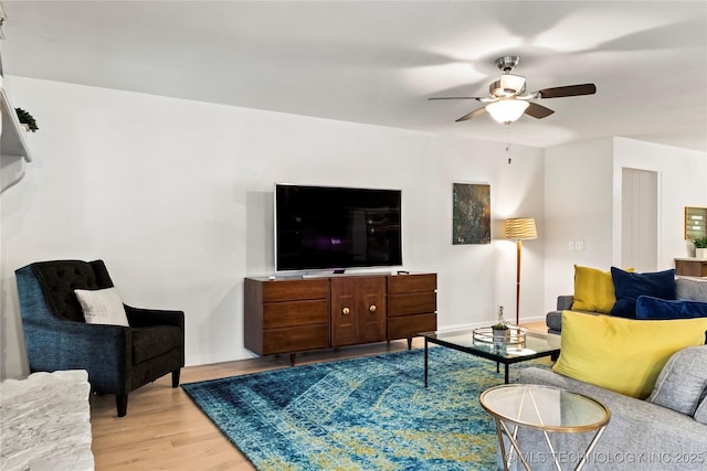 living area with light wood-type flooring, ceiling fan, and baseboards