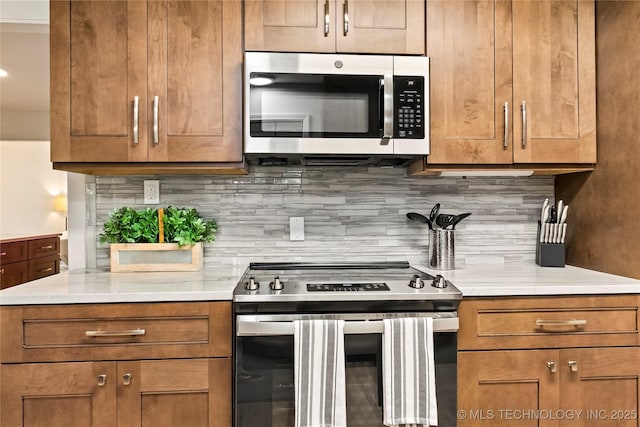 kitchen with light countertops, appliances with stainless steel finishes, brown cabinets, and decorative backsplash