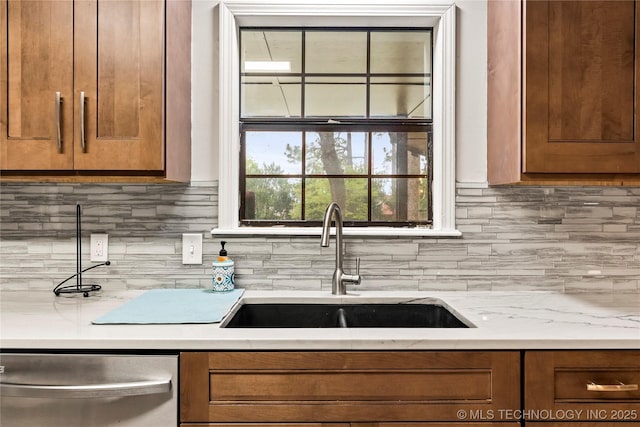 kitchen featuring stainless steel dishwasher, a sink, and brown cabinets