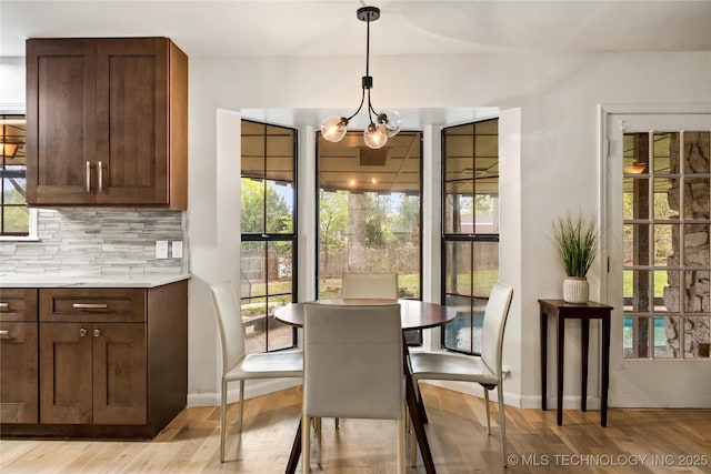 dining room featuring baseboards, light wood finished floors, and an inviting chandelier