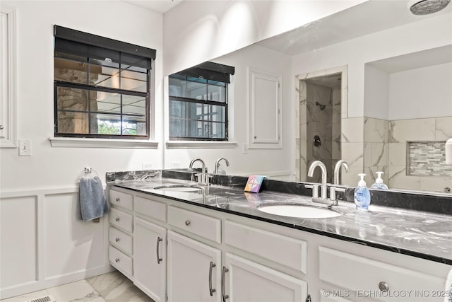 bathroom with a shower, marble finish floor, a sink, and double vanity