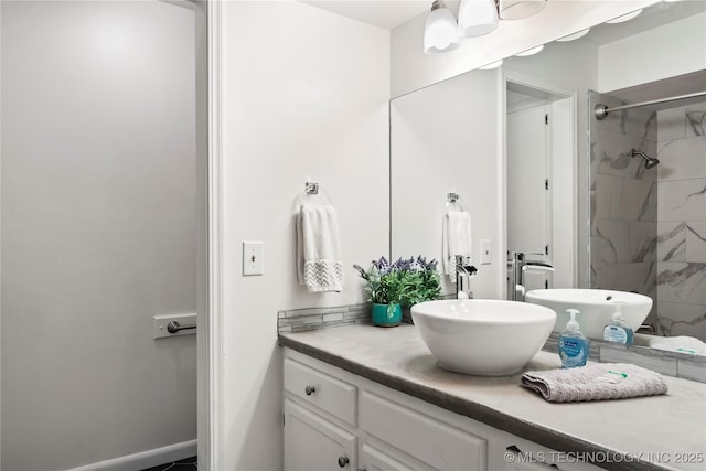 bathroom featuring tiled shower, vanity, and baseboards