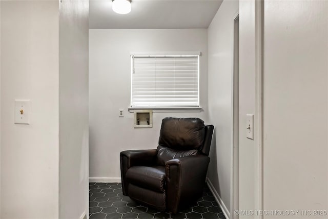 living area featuring dark tile patterned floors and baseboards