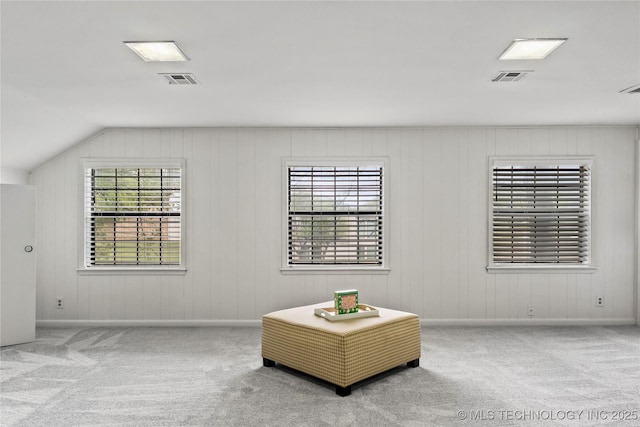 living area with carpet, visible vents, vaulted ceiling, and baseboards