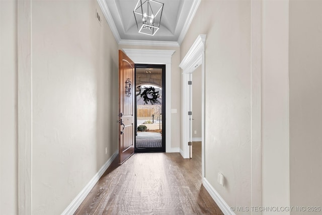 doorway featuring ornamental molding, dark wood-type flooring, and a chandelier