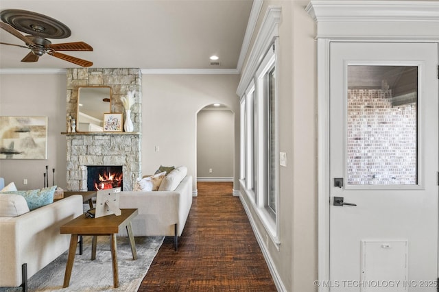 living room featuring crown molding, a ceiling fan, arched walkways, and a fireplace