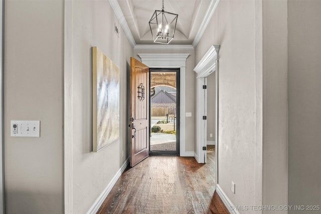 doorway with a chandelier, baseboards, ornamental molding, and wood finished floors