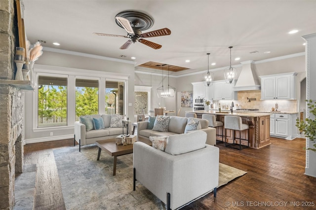 living room with ornamental molding, recessed lighting, dark wood-style floors, and ceiling fan with notable chandelier