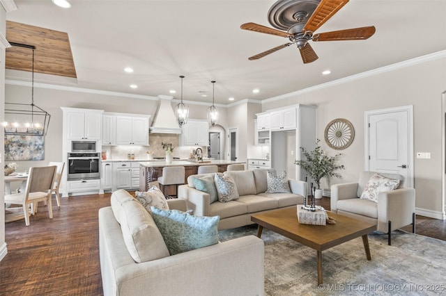 living room featuring ceiling fan with notable chandelier, baseboards, ornamental molding, and recessed lighting