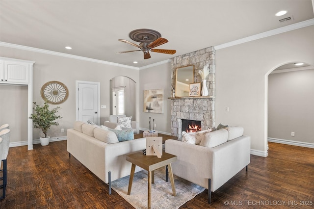 living area with visible vents, arched walkways, a stone fireplace, a ceiling fan, and wood finished floors