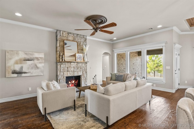 living room featuring a stone fireplace, arched walkways, wood finished floors, and baseboards