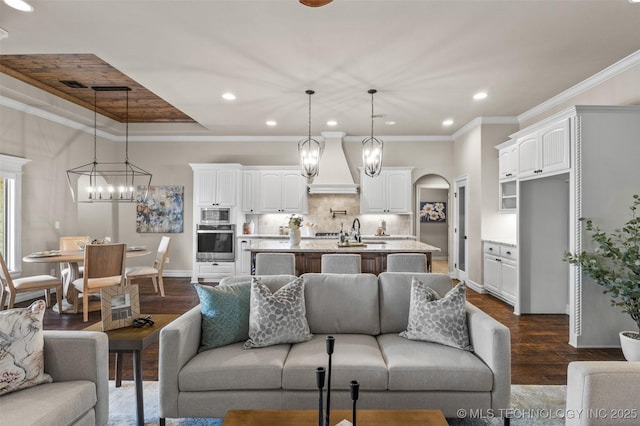 living room with baseboards, an inviting chandelier, recessed lighting, dark wood-type flooring, and arched walkways