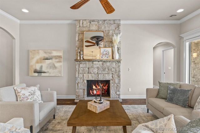 living area featuring arched walkways, a ceiling fan, crown molding, and wood finished floors