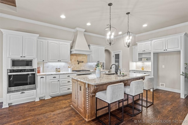 kitchen featuring custom exhaust hood, appliances with stainless steel finishes, a sink, and white cabinets
