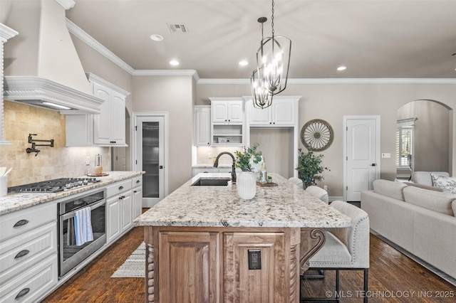 kitchen with custom exhaust hood, visible vents, a breakfast bar area, appliances with stainless steel finishes, and a sink