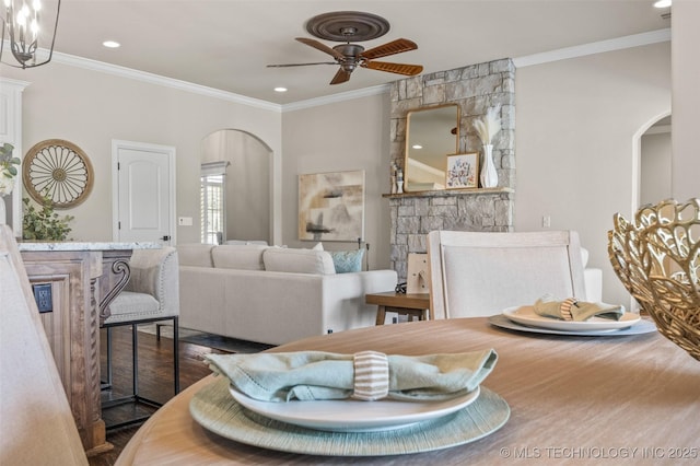 interior space featuring crown molding, ceiling fan, arched walkways, and wood finished floors
