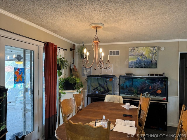 dining area featuring crown molding, a chandelier, and a textured ceiling