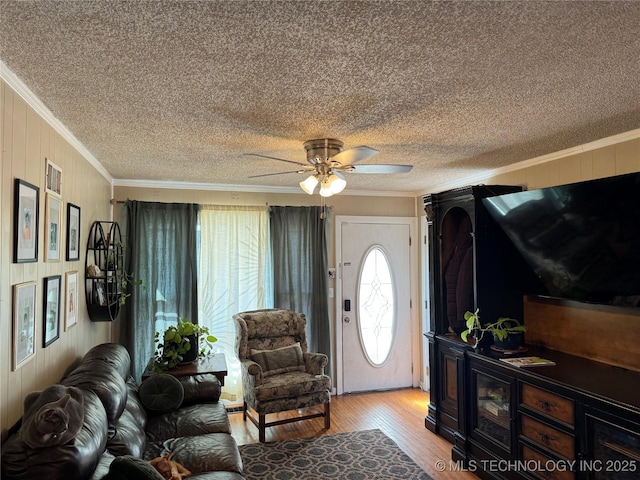 living room featuring ceiling fan, ornamental molding, wooden walls, and light wood-type flooring