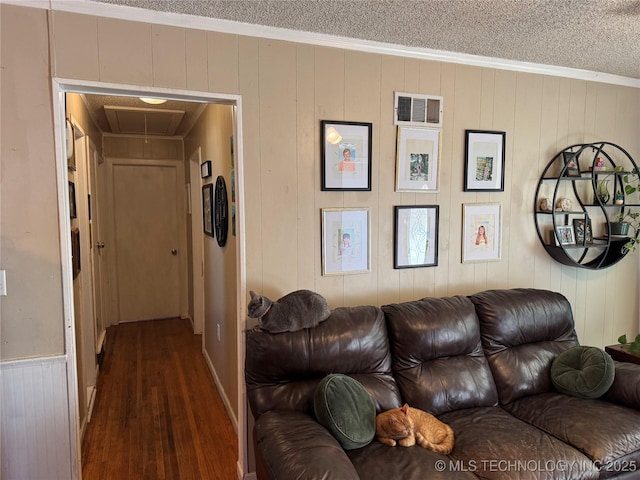 living room with ornamental molding, dark hardwood / wood-style floors, a textured ceiling, and wood walls