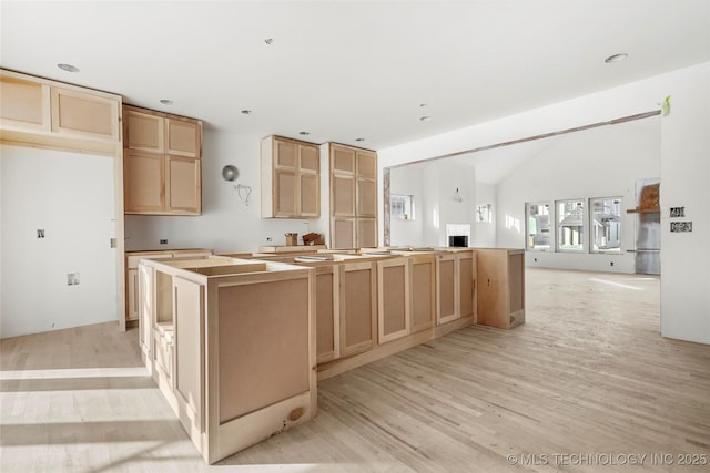 kitchen with light wood-type flooring, a kitchen island, and light brown cabinetry