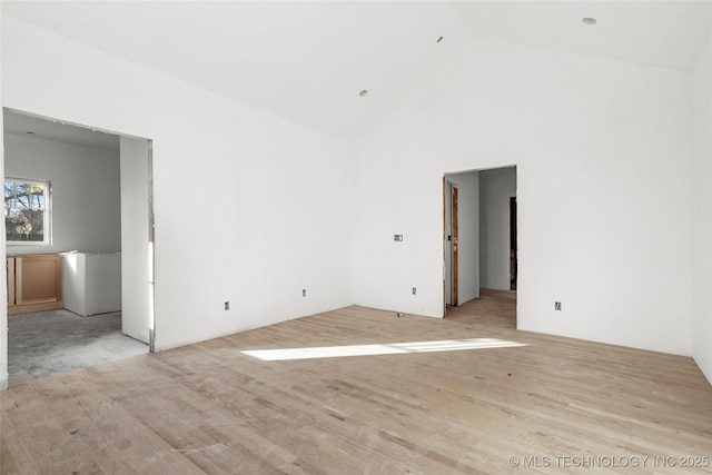 empty room with high vaulted ceiling and light hardwood / wood-style floors