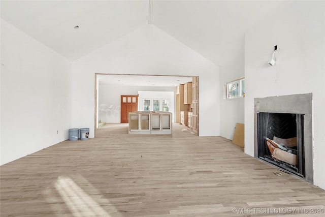 unfurnished living room with high vaulted ceiling and light hardwood / wood-style flooring