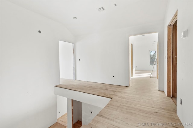 hall featuring lofted ceiling and light hardwood / wood-style floors