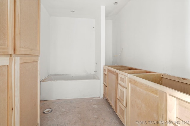 bathroom with a tub to relax in and concrete flooring