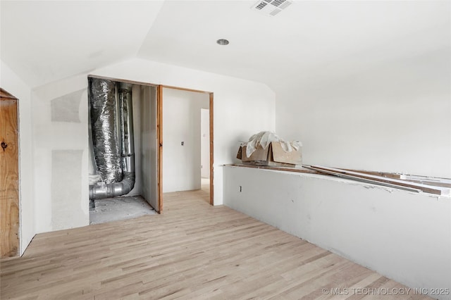 corridor with vaulted ceiling and light hardwood / wood-style flooring