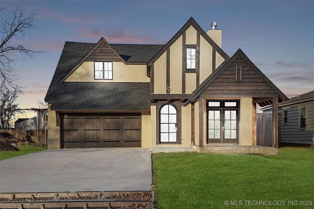 tudor house with a garage, french doors, and a yard