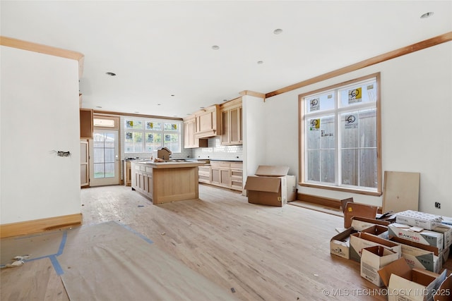 kitchen featuring light brown cabinetry, decorative backsplash, crown molding, and a kitchen island