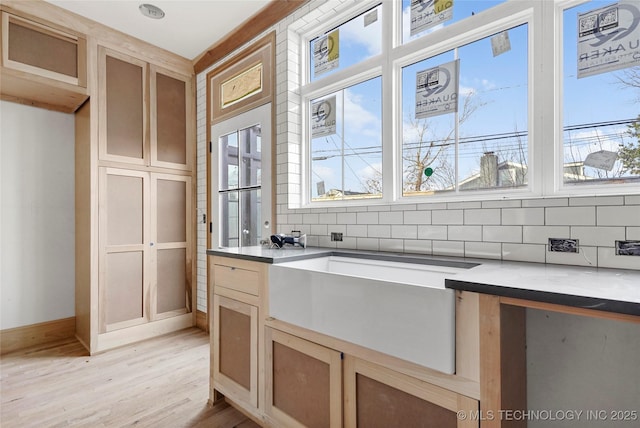 kitchen with light brown cabinetry, light hardwood / wood-style floors, and tasteful backsplash