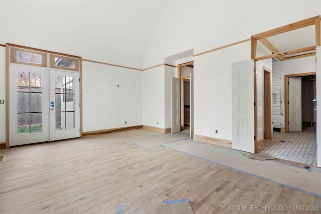 unfurnished room featuring light hardwood / wood-style floors, high vaulted ceiling, and french doors