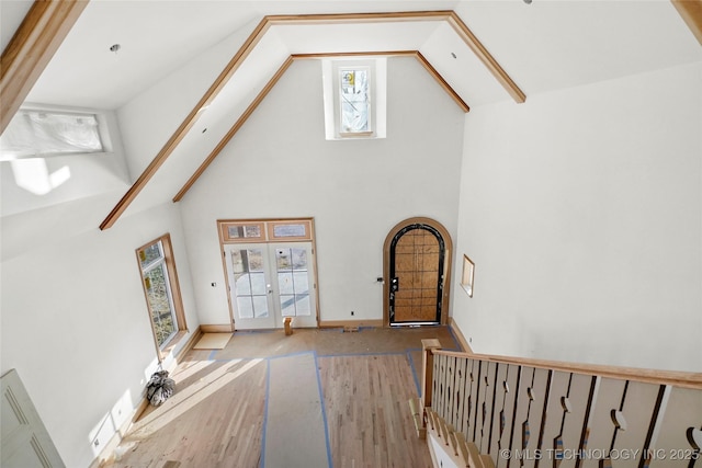 living room featuring french doors, beam ceiling, light hardwood / wood-style flooring, and high vaulted ceiling