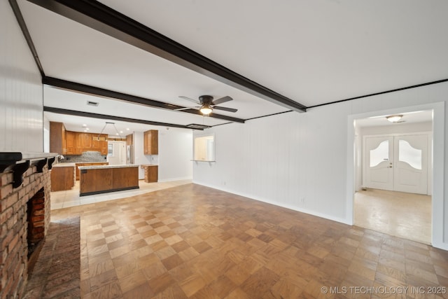 unfurnished living room with ceiling fan, light parquet flooring, french doors, and beamed ceiling