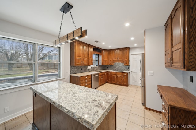 kitchen with stainless steel appliances, backsplash, hanging light fixtures, and light stone countertops