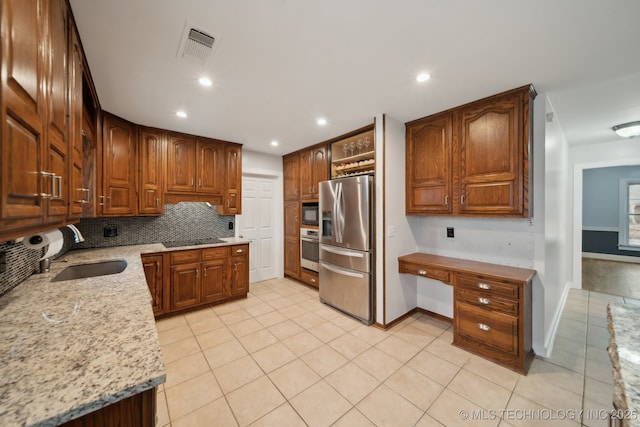 kitchen featuring light stone countertops, black appliances, tasteful backsplash, sink, and light tile patterned flooring