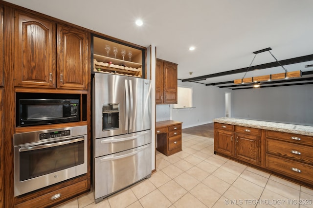 kitchen with appliances with stainless steel finishes, beam ceiling, and light stone counters