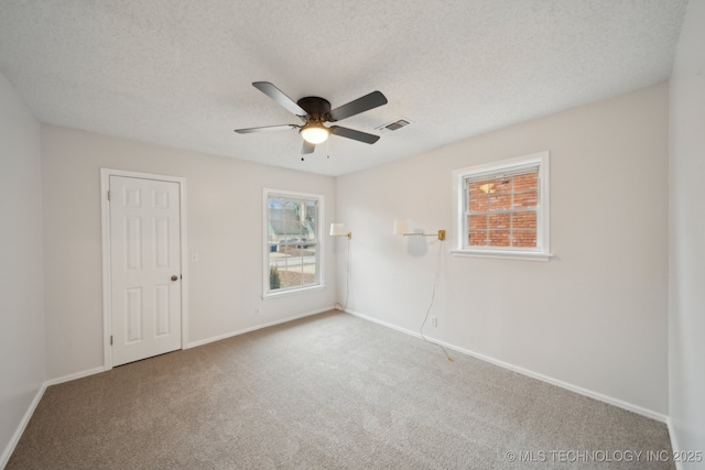 spare room with a textured ceiling, carpet flooring, and a healthy amount of sunlight