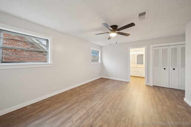 unfurnished bedroom with ceiling fan, ensuite bath, a closet, and multiple windows