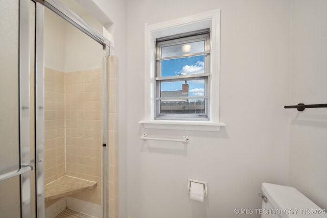 bathroom with toilet and a shower with door