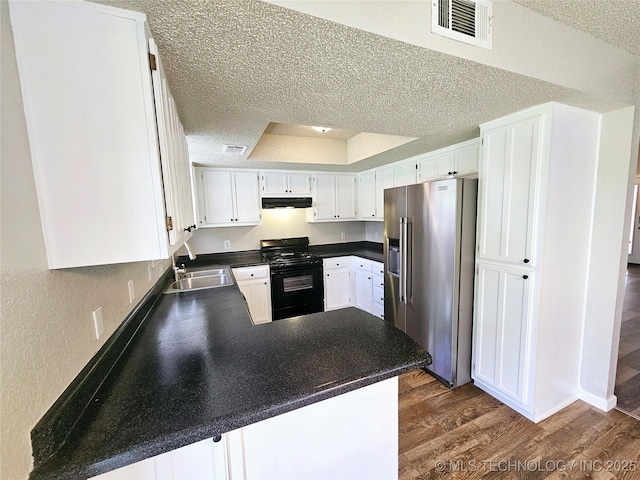 kitchen featuring kitchen peninsula, black range with gas cooktop, high end fridge, a textured ceiling, and white cabinets