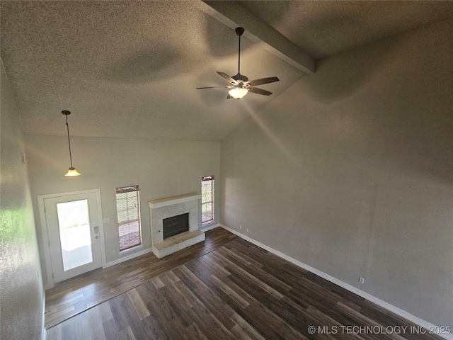 unfurnished living room featuring dark wood-type flooring, lofted ceiling with beams, a fireplace, and a textured ceiling