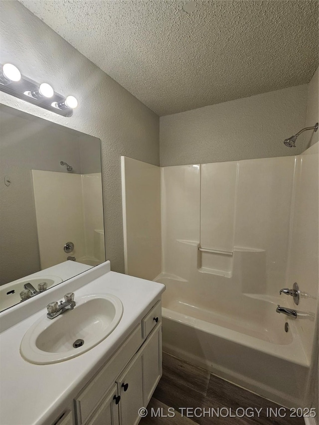 bathroom with bathtub / shower combination, vanity, a textured ceiling, and hardwood / wood-style floors