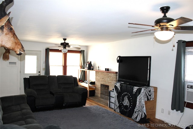 living room featuring ceiling fan, a healthy amount of sunlight, a brick fireplace, and hardwood / wood-style flooring