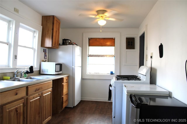 kitchen with dark wood-type flooring, sink, white appliances, and ceiling fan