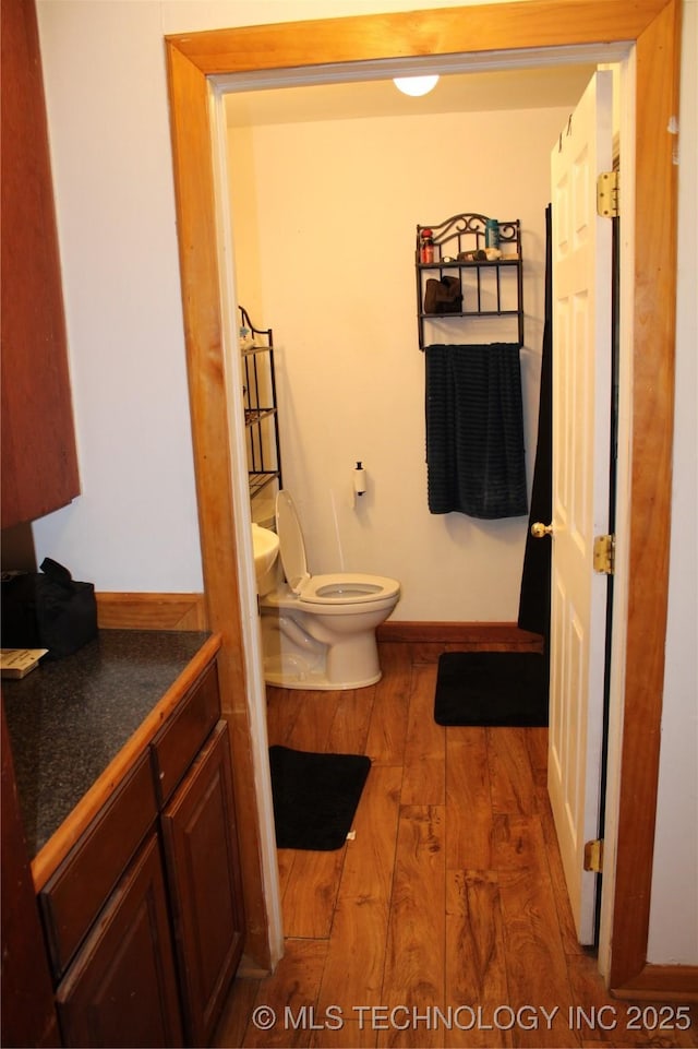 bathroom with hardwood / wood-style flooring, toilet, and vanity