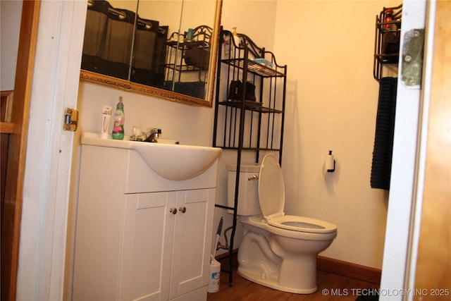 bathroom with hardwood / wood-style flooring, toilet, and vanity