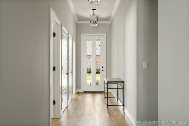 corridor featuring an inviting chandelier, ornamental molding, light hardwood / wood-style flooring, and plenty of natural light