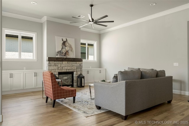 living room featuring light hardwood / wood-style floors, ornamental molding, ceiling fan, and a fireplace